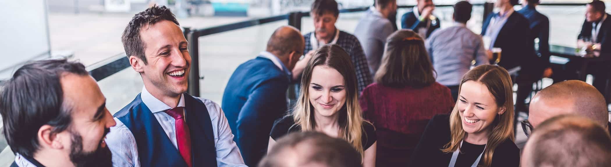 Die Teilnehmer eines Teambuilding Events lernen bei einem Zauberworkshop Zaubertricks. Dabei lachen sie und haben Spaß.