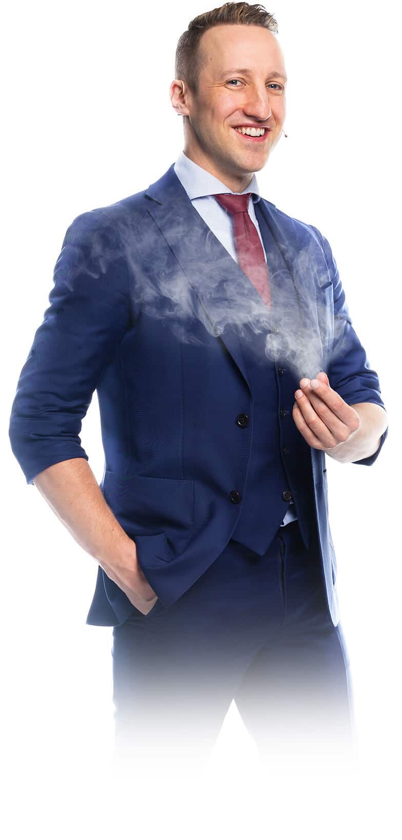 The professional magician and magical artist in Munich (Fabian Schneekind) is smiling into the camera, while magical smoke is developing at his fingertips. You can book him as a magical entertainer, closeup magician, wedding magician and corporate event magician.